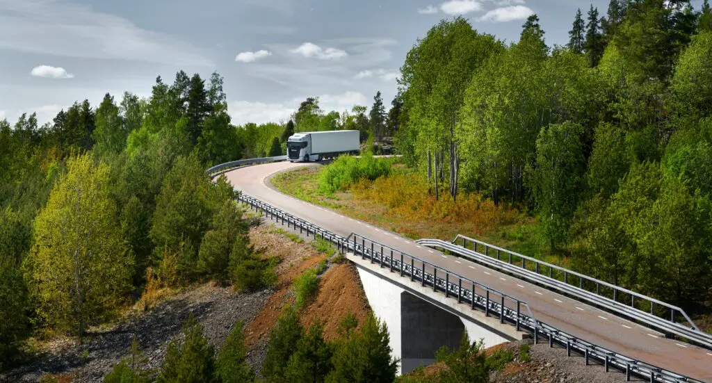 truck driving on road through forest